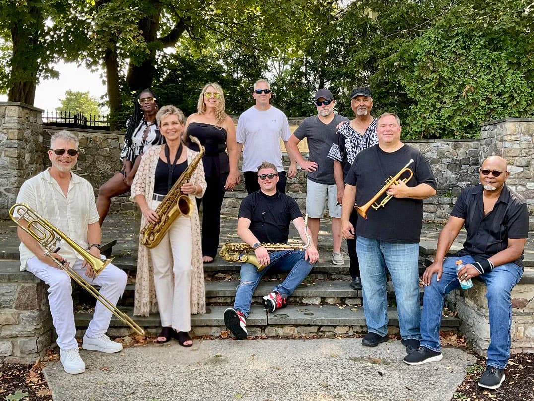 Members of the Diana Jacobs Band gathered outdoors with saxophones, trumpet, and trombone